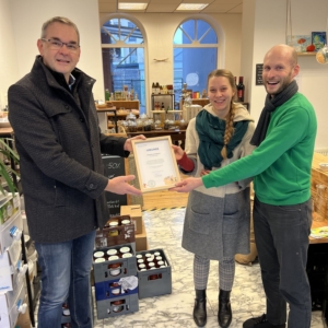 Bürgermeister Stefan Rosemann übergibt eine Urkunde an Samira Clijsters und Christian Grohmann vom Team Siegburg Unverpackt.